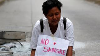 Una joven con un cartel que dice "No más sangre"