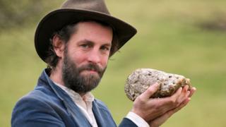 man holding whale dung stone