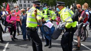 An activist from the climate protest group Extinction Rebellion is carried away by police officers