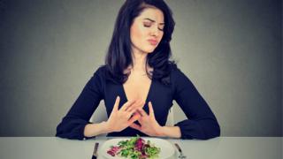 Mujer rechazando un plato de verduras
