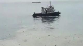 Boat in water surrounded by oil