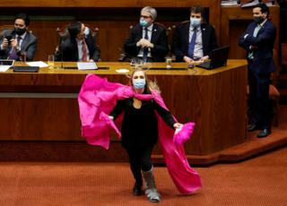A congresswoman dances with a purple cape