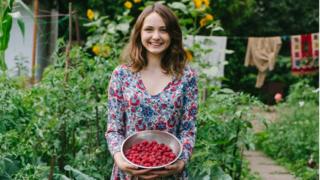 Mujer con frutas del bosque en un jardín.