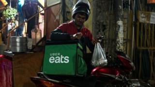 In this photograph taken on February 6, 2019, an Indian delivery man working with the Uber Eats food delivery app loads up food to bring to a customer in New Delhi.
