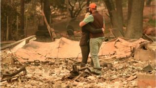 A couple embraces while looking over the remains of their burned residence after the Camp fire tore through the region in Paradise, California