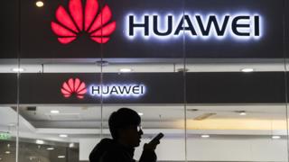 Человек стоит перед логотипом Huawei