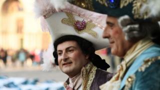 Two men in costumes stand in Venice
