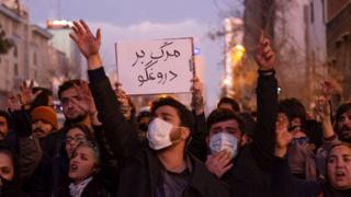 Iranians shout slogans as one of them holds-up a placard with a Persian script that reads, Death To The Liar, during a gathering to mark the victims of the crash