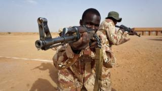 Two African soldiers aim guns in the desert