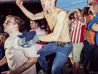 Craig Nickels, 37, rejoices with his friends in the final records of the Brentford football match in West London.