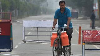 పాల క్యాన్లతో వెళ్తున్న వ్యక్తి