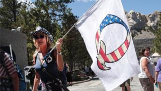 A Donald Trump supporter holding a QAnon flag visits Mount Rushmore National Monument on 01 July 2020