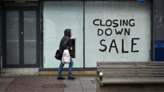 A pedestrian walks past a boarded-up shop in Sunderland