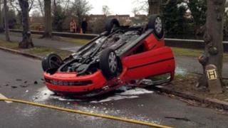 A red Vauxhall Corsa on its roof