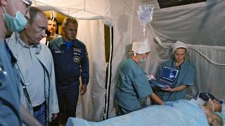 Vladimir Putin (2nd L) looks at a man injured during fighting in South Ossetia during a visit to a field hospital in Vladikavkaz, the provincial capital of the region of North Ossetia