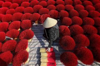 A woman collects dried incense sticks