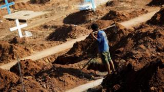 A worker prepares graves at the Sao Sebastiao cemetery in Altamira, Brazil