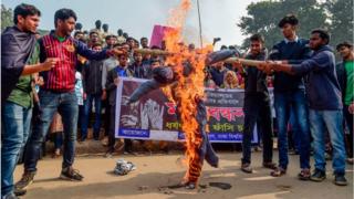 ঢাকা বিশ্ববিদ্যালয়ের রাজু ভাস্কর্যের সামনে ধর্ষকের প্রতীকী কুশপুত্তলিকা পোড়ায় বিক্ষোভকারী শিক্ষার্থীরা।