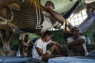 Insassen sitzen in ihrer Zelle, während andere in Hängematten im Chalatenango Penal Center in El Salvador am 7. November 2018 liegen