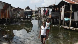 Children paddle in water in a Nigerian shanty town
