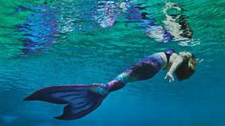 Mulher vestida de sereia em parque temático