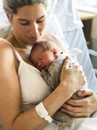 A woman holds a newborn baby