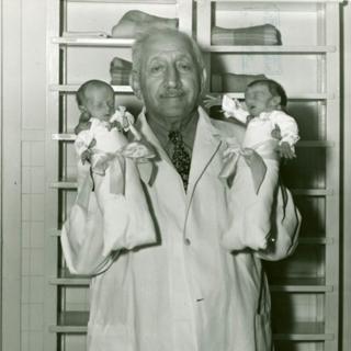 Martin Couney cargando dos bebés