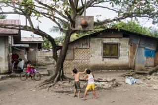 Children shoot hoops in a yard