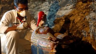 Египетский работник древностей работает над гробом в недавно обнаруженной гробнице Аменемхата, ювелира из Нового Царства, в некрополе Драа Абу-эль-Нага близ города Нил в Луксоре
