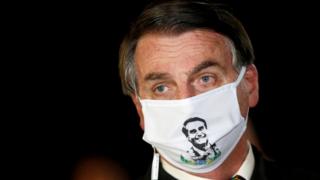 El presidente Jair Bolsonaro habla con periodistas mientras usa una máscara facial protectora cuando llega al Palacio de Alvorada, en medio del brote de la enfermedad por coronavirus (COVID-19), en Brasilia, Brasil, el 22 de mayo de 2020.