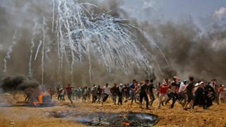イスラエル軍が撃ち込んだ催涙ガス弾から逃げるパレスチナ人たち(14日、ガザ地区)