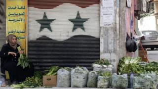 File photo showing a woman selling vegetables in the government-held Jaramana district of Damascus (21 February 2018)