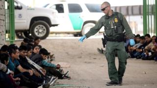 A border official pointing at migrants caught after crossing the US border