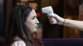 A woman has her temperature checked before entering the Coyote Ugly bar on St. Mary's Street on September 10, 2020 in Cardiff, Wales.