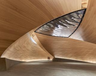 An interior of a building with a sloping wooden ceiling