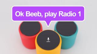 A photo illustration shows a floating speech bubble over three smart speakers, with the speech bubble reading "Ok Beeb, play Radio 1"