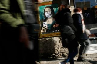 in_pictures People walk by a poster by Italian urban artist Salvatore Benintende aka 