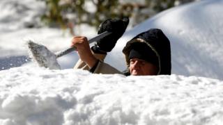 A man cleans the snow from the top of his vehicle in Detroit, Michigan, 12 November, 2019