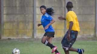 Girl is chased by a boy on a football pitch