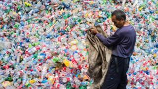 Китайский рабочий перебирает пластиковые бутылки