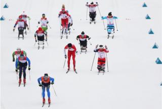 Skiers race on a ski slope in the Mixed Relay Cross-Country Skiing