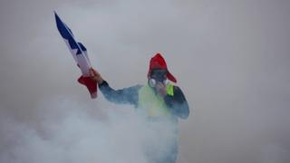 Демонстрант храбрит слезоточивый газ на парижской акции протеста - 1 декабря