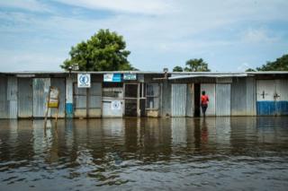 A woman enters a row of kiosks that are flooded.
