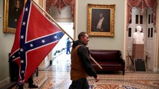 A supporter of President Donald Trump carries a Confederate battle flag on the second floor of the U.S. Capitol