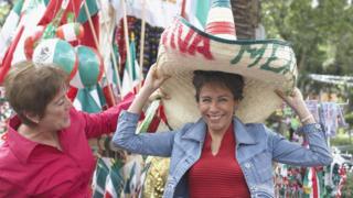 Dos mujeres, una de ellas con un sombrero que dice "Viva México".
