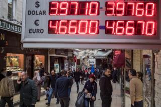 لوحة أسعار صرف الليرة التركية في الشارع وأشخاص في السوق