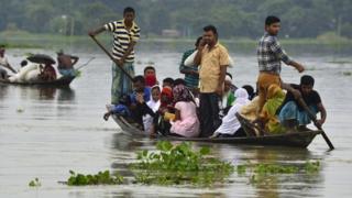 Pessoas em barcos tentam escapar da inundação em Assam, na Índia