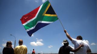 Des personnes tenant le drapeau de l'Afrique du Sud