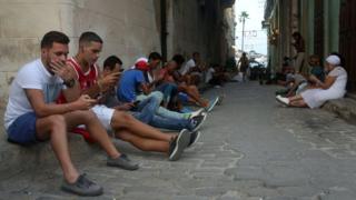 Personas conectándose a Internet a través de sus teléfonos celulares en La Habana.