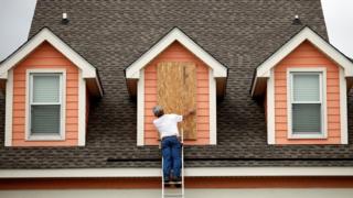 Un hombre coloca una protección de madera en la ventana de su casa en Carolina del Sur.